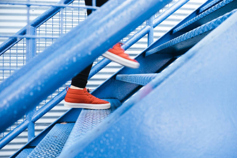close up view of person with red sneakers walking up stairs